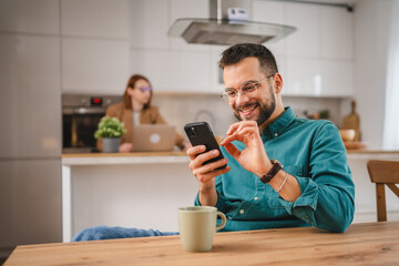 man with eyeglasses stand at home use mobile phone sms texting