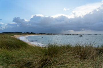 Oyats bordant une plage bretonne sous un ciel couvert : la poésie sauvage de la côte bretonne.