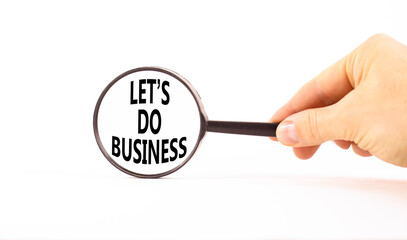 let is do business symbol. Concept words let is do business in beautiful magnifying glass. Beautiful white table white background. Businessman hand. let is do business concept. Copy space.