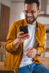 Obraz na płótnie Canvas man with eyeglasses stand at home use mobile phone sms texting