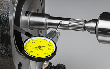 Closeup a shaft run-out measurement by yellow dial test indicator with metal probe on hinge and...