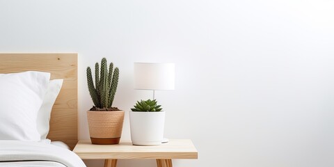 Morning with white, stylish, minimalistic, rustic or Scandinavian sunny bedroom. A cactus stands on a wooden table, next to a black lamp. Horizontal copy space is empty.