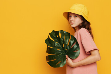 Young woman with green leaf on yellow background