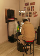 Man Seated Alone at a Makeshift Bar with Whiskey Bottle