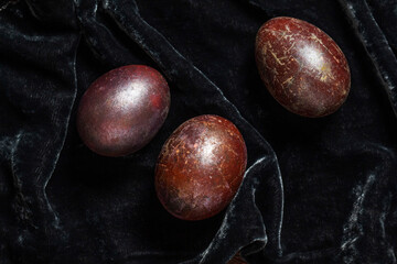 Eggs stained with wine and covered with mother-of-pearl on a dark velvet background. Easter concept.