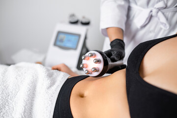 RF body cavitation lifting procedure is employed at the beauty salon to aid a young woman in...