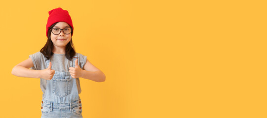 Portrait of stylish little girl showing thumb-up gesture on color background