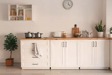 White counters with electric stove, cooking pots and utensils in modern kitchen