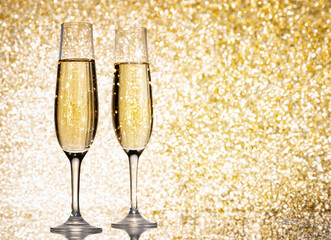 flutes with champagne or fizzy white wine on black background with blurred sparkles in the back