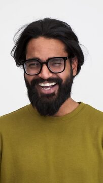 Portrait of cheerful handsome young man with beard laughing ecstatically and gesturing while looking at camera over isolated white background