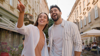 Obraz premium Young Caucasian happy couple walking city outside street cafe attractions man woman smiling laughing hug embrace tourism trip enjoy together love married relationship feeling honeymoon dating journey
