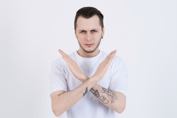 Upset or angry attractive caucasian young man with tattoos in casual clothes showing stop gesture...