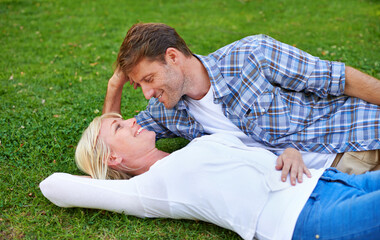 Couple, relax on grass and bonding in park for love, trust in commitment and marriage. Happy people on date, together outdoor for fresh air and romance with support, loyalty and peace on picnic