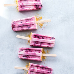 Cherry yogurt pops in a line against a light rustic surface.