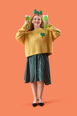 Young woman with beer on orange background. St. Patrick's Day celebration
