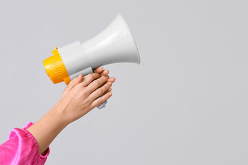 Female hands with megaphone on grey background