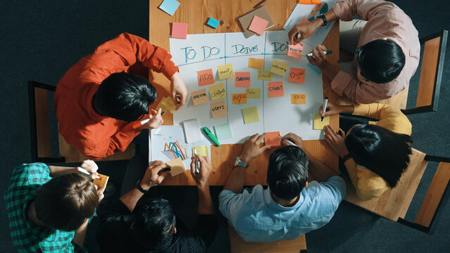 Top view of people writing and making scrum task board while writing marketing and planning strategy at colorful sticky notes. Smart team manage work performance by using kanaban board. Convocation.