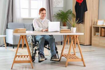 Male graduate in wheelchair using laptop at home