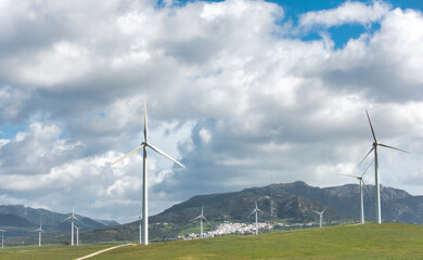 Renewable energy concept with windmills on a grassy field against a cloudy sky - 753263681