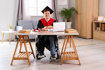 Male graduate in wheelchair near table at home