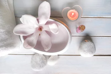 Foto auf Acrylglas Antireflex beautiful pink magnolia flower, smooth white stones in a stack, candles, white towel, concept of wellness spa treatments for the beauty of body and soul, massage, zen stone in the pool of serenity © kittyfly