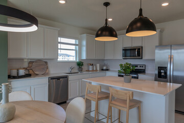 Modern white Farmhouse kitchen with black hanging lights,  breakfast nook and white cabinets