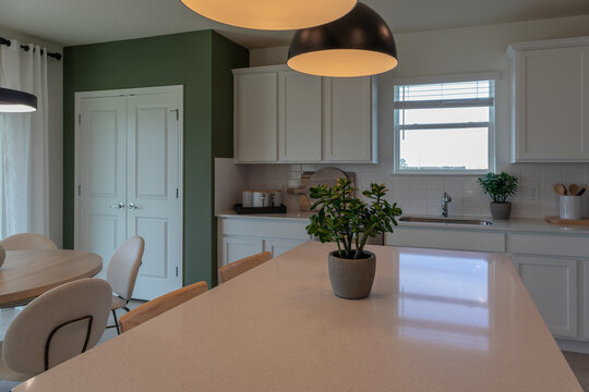 Farmhouse style kitchen with white Corian counter, black hanging pendant lights and kitchen island