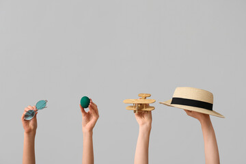 Female hands holding hat with sunglasses, toy plane and Easter egg on white background. Holiday...
