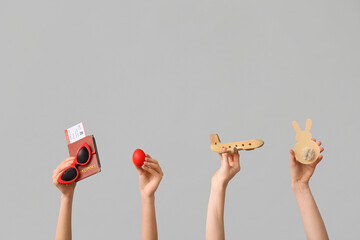 Female hands holding passport with toy plane, paper bunny and Easter egg on white background....