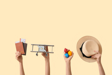 Female hands holding passports with hat, toy plane and Easter eggs on beige background. Holiday...
