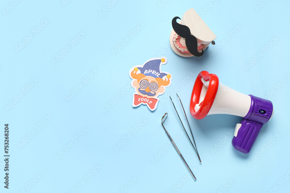 Sticker Model of jaw with paper mustache, megaphone and dentist tools on blue background. April Fools Day