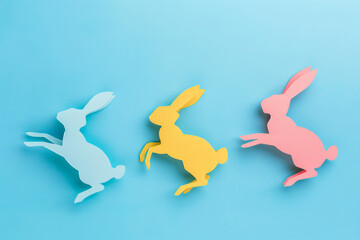 Colorful paper bunnies on blue background. Easter concept.