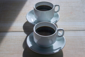 Two white cups with black coffee on the table close-up.