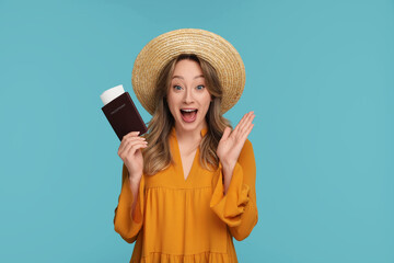 Emotional young woman with passport, ticket and hat on light blue background