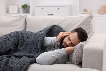 Man suffering from headache on sofa at home