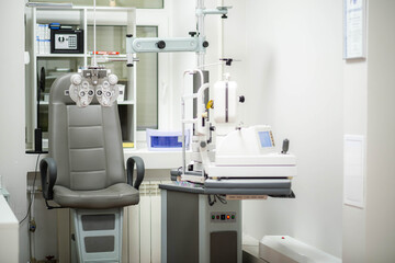 Ophthalmological cabinet with modern equipment in a medical clinic featuring an examination chair and phoropter, ready for vision testing and eye health assessments - obrazy, fototapety, plakaty