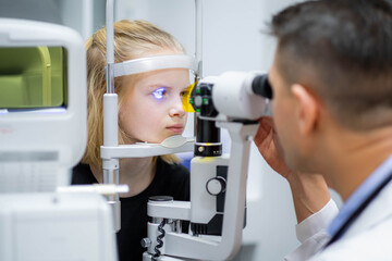 doctor and young patient in eye clinic, girl undergoing an eye test with professional optometrist...