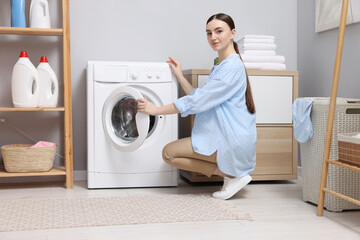 Beautiful woman near washing machine in laundry room