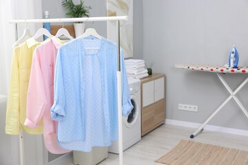 Laundry room interior with washing machine and clothes on rack