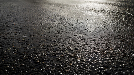 Advertising shot of perfect withour cracks wet black asphalt road texture highlighted with light from the side