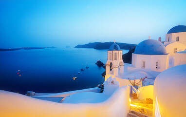 traditional greek village Oia of Santorini, with blue domes of churches and village roofs at night, Greece
