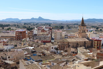 Villena, Alicante, Spain, March 5, 2024: Building and Bell Tower of the Church of Santa Maria in the center of the town with mountains in the background. Villena, Alicante, Spain