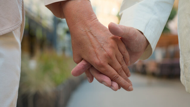 Close up unrecognizable wrinkled hand elderly old senior aged man and woman married couple husband wife holding hands separated palms outside marriage problems family relationship divorce separation