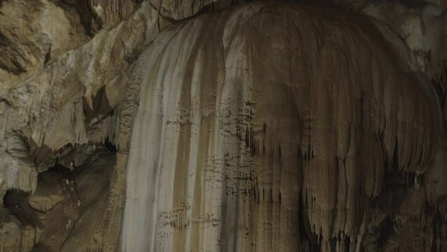 A girl takes pictures of stalagmites on the wall in a cave on her phone