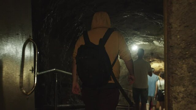 A man with a backpack goes down the stairs to an underground bunker