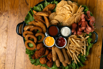 A large plate of snacks, the plate is garnished with green lettuce and sits on a wooden table in a...