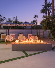 Outdoor backyard patio at night with a fireplace and chairs