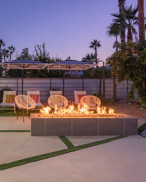 Outdoor backyard patio at night with a fireplace and chairs