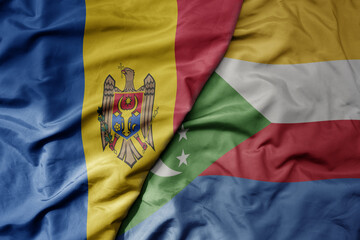 big waving national colorful flag of comoros and national flag of moldova .