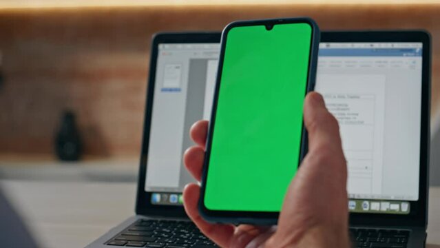 Man hand touching green screen mobile answering videocall at workplace closeup